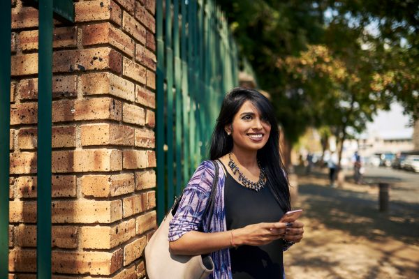 Medium shot of a young woman smiling while standing on a street waiting for her ride