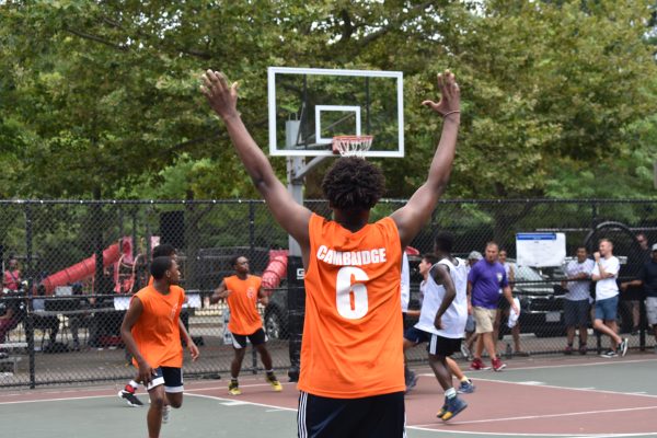 Basketball player in Cambridge shirt raises his hands in victory