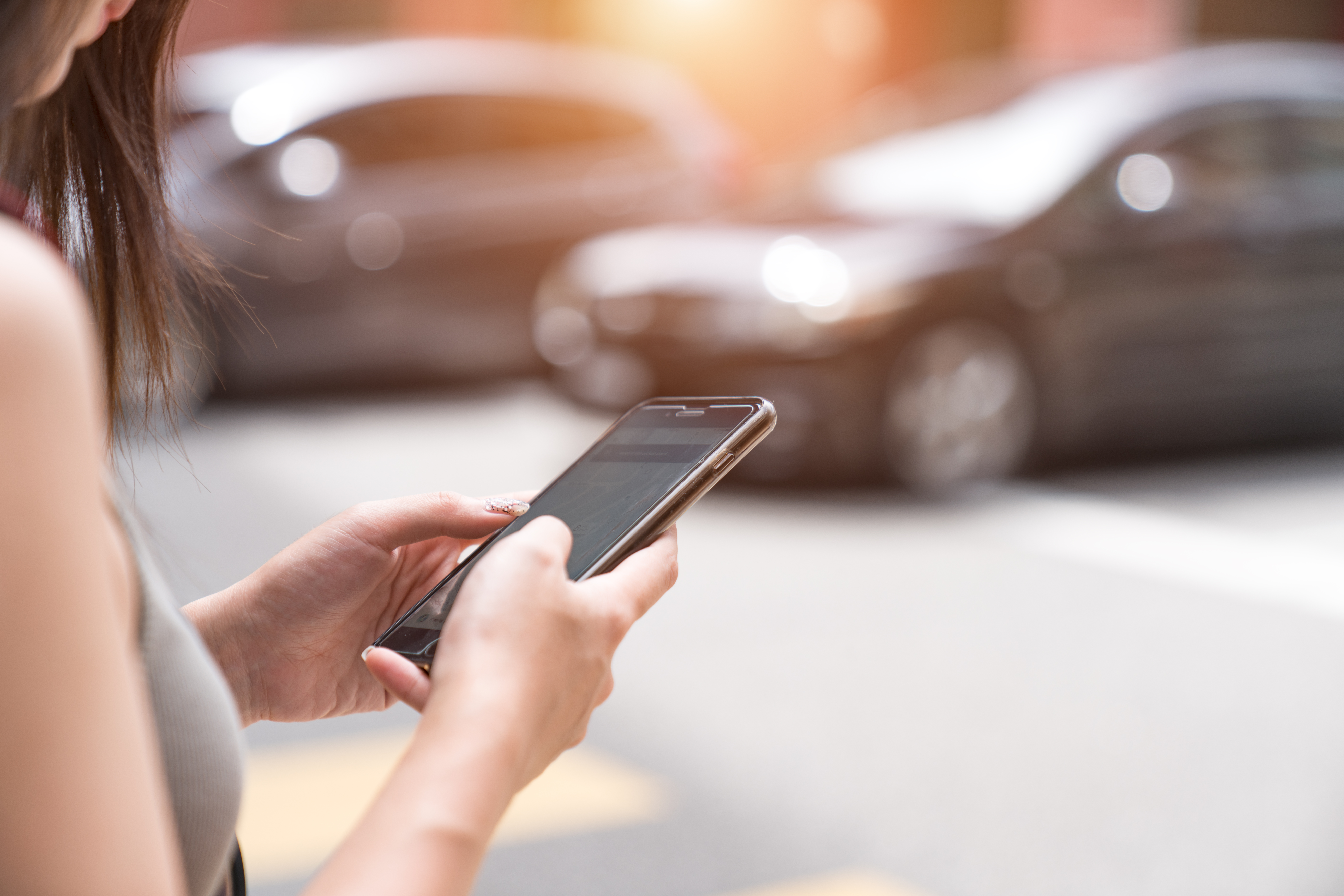 Woman using taxi app on mobile phone A woman uses her phone to call a rideshare service
