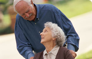 elderly_couple_wheelchair An older man pushes an older woman in a wheelchair