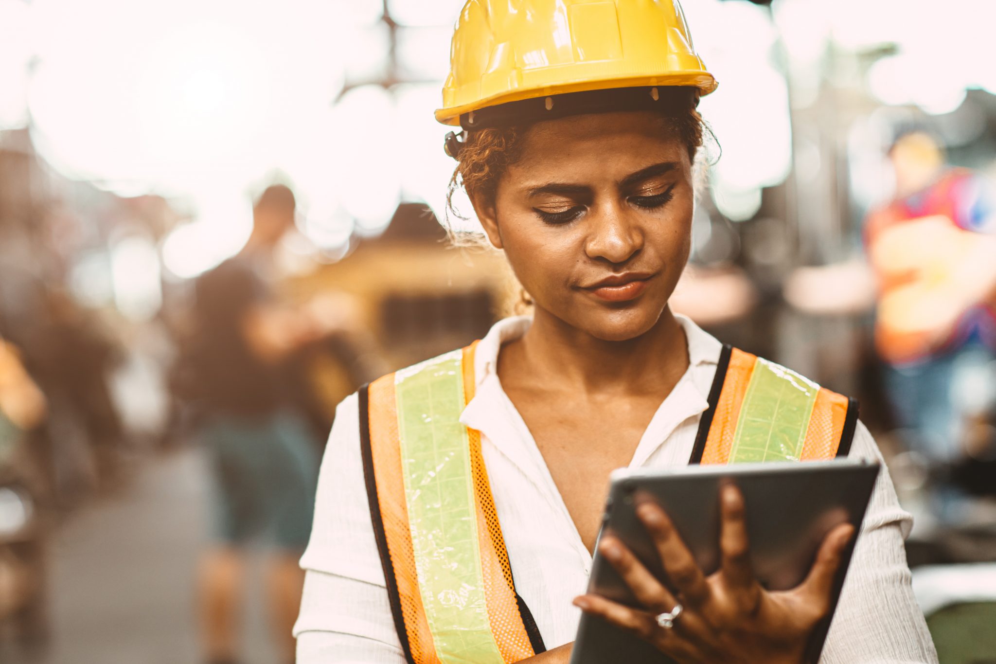 Female maintenance worker American women worker in heavy Industry maintenance engineer happy working wearing safety uniform and helmet using tablet computer to checking machine in factory.