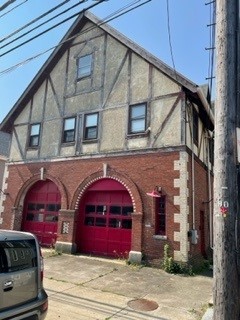 Image is of the front of a brick firehouse that has two bright red garage doors.