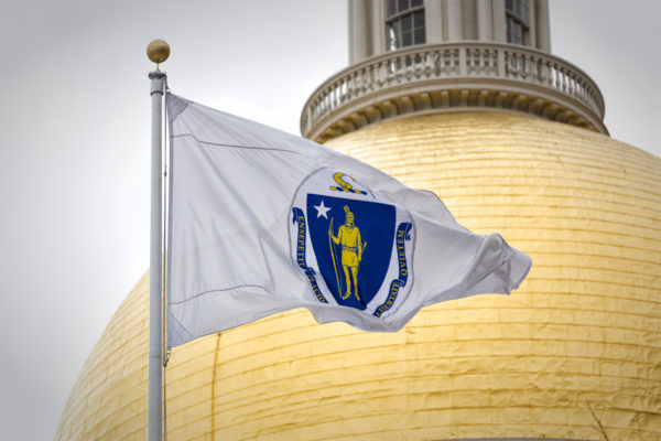 Photo is the gold dome of the Massachusetts state capital building, and a flag waving infront of it.