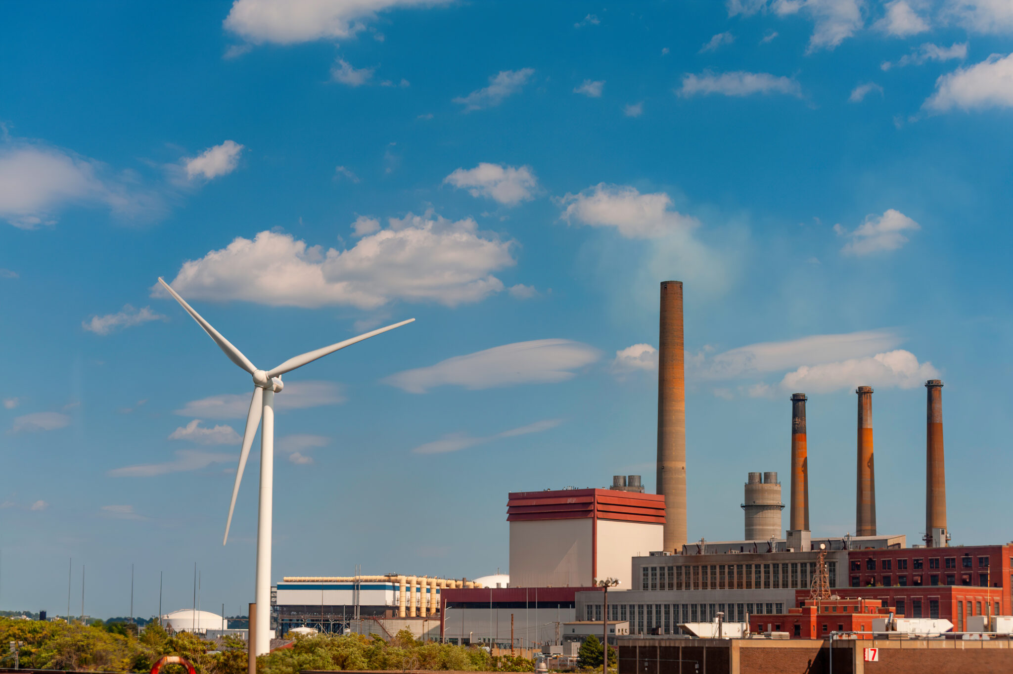 A wind turbine and factory are seen from a window of a moving train traveling to Salem, Massachusetts