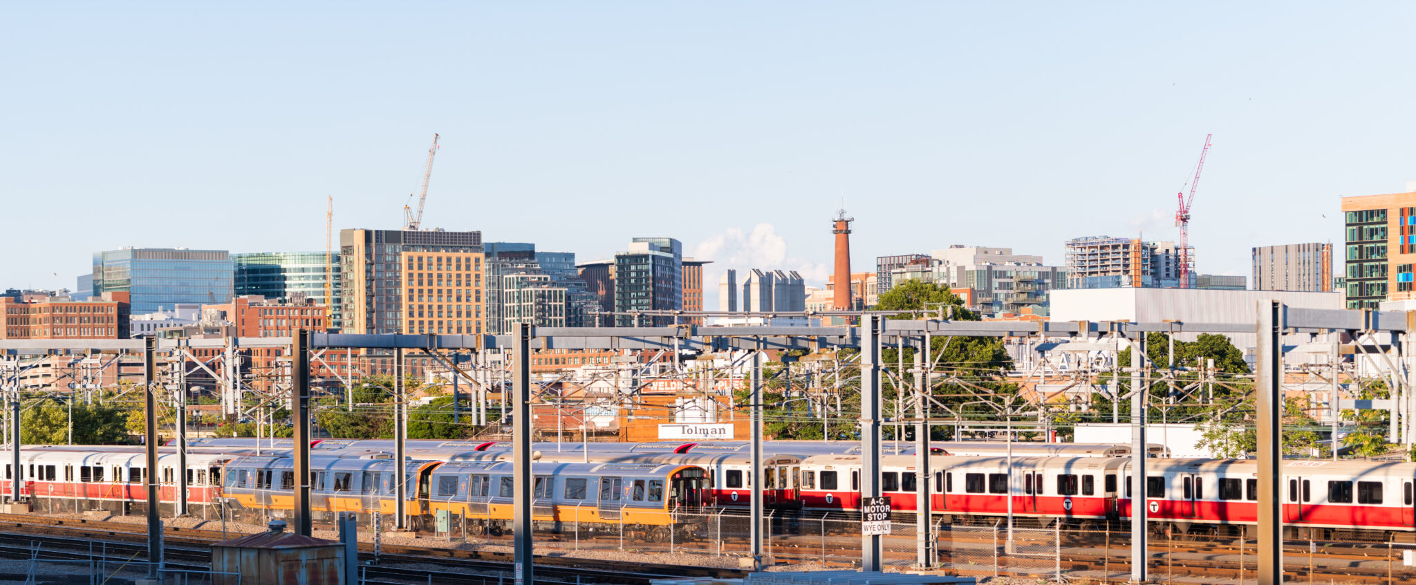 Redline MBTA train with buildings in the background behind the train going by.
