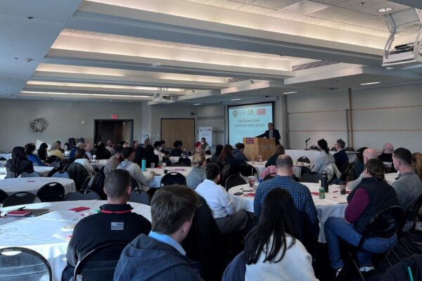 Photo of the Shannon 2023 summit: a large conference room with attendees sitting at tables. MAPC Executive Director Marc Draisen speaks from a podium.