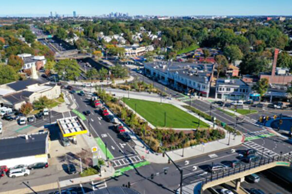 An aerial view of East Milton. There are streets with vehicles, buildings, grassy areas and a lot of trees.