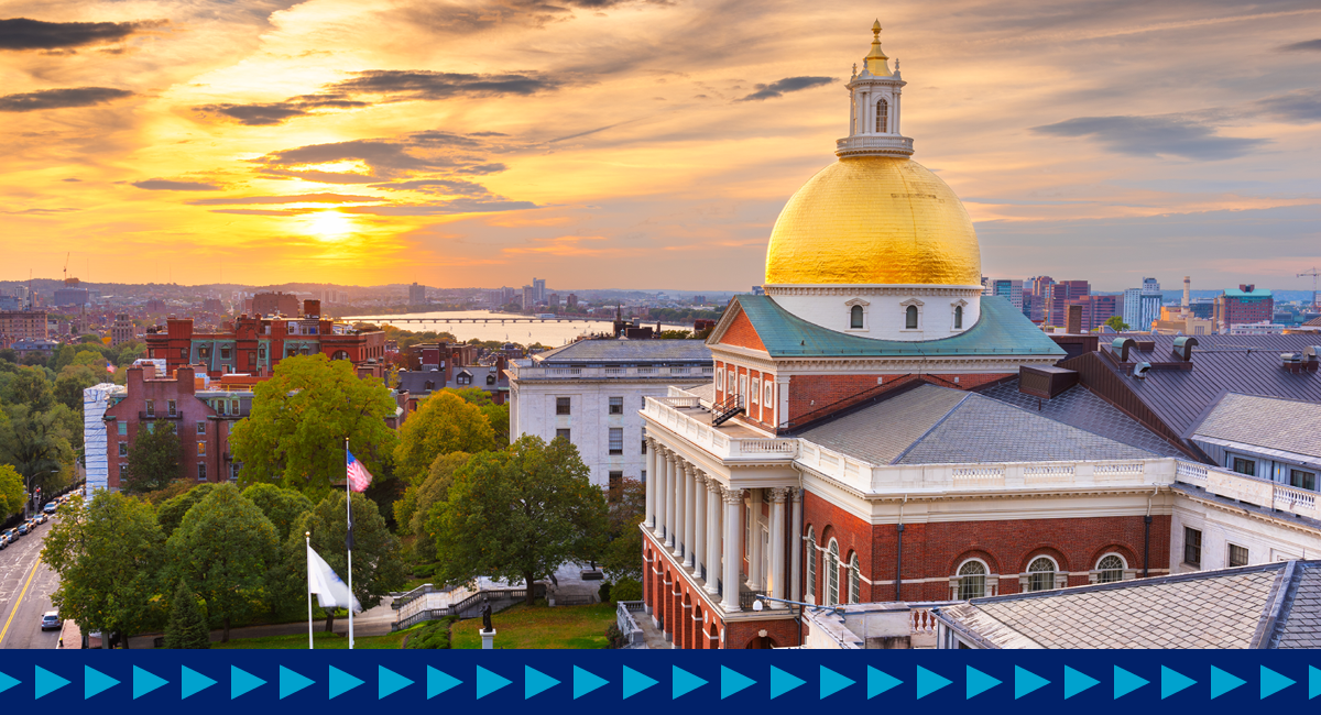 Aerial photo of the Massachusetts State House looking at the side of the building with a sunset in the background.