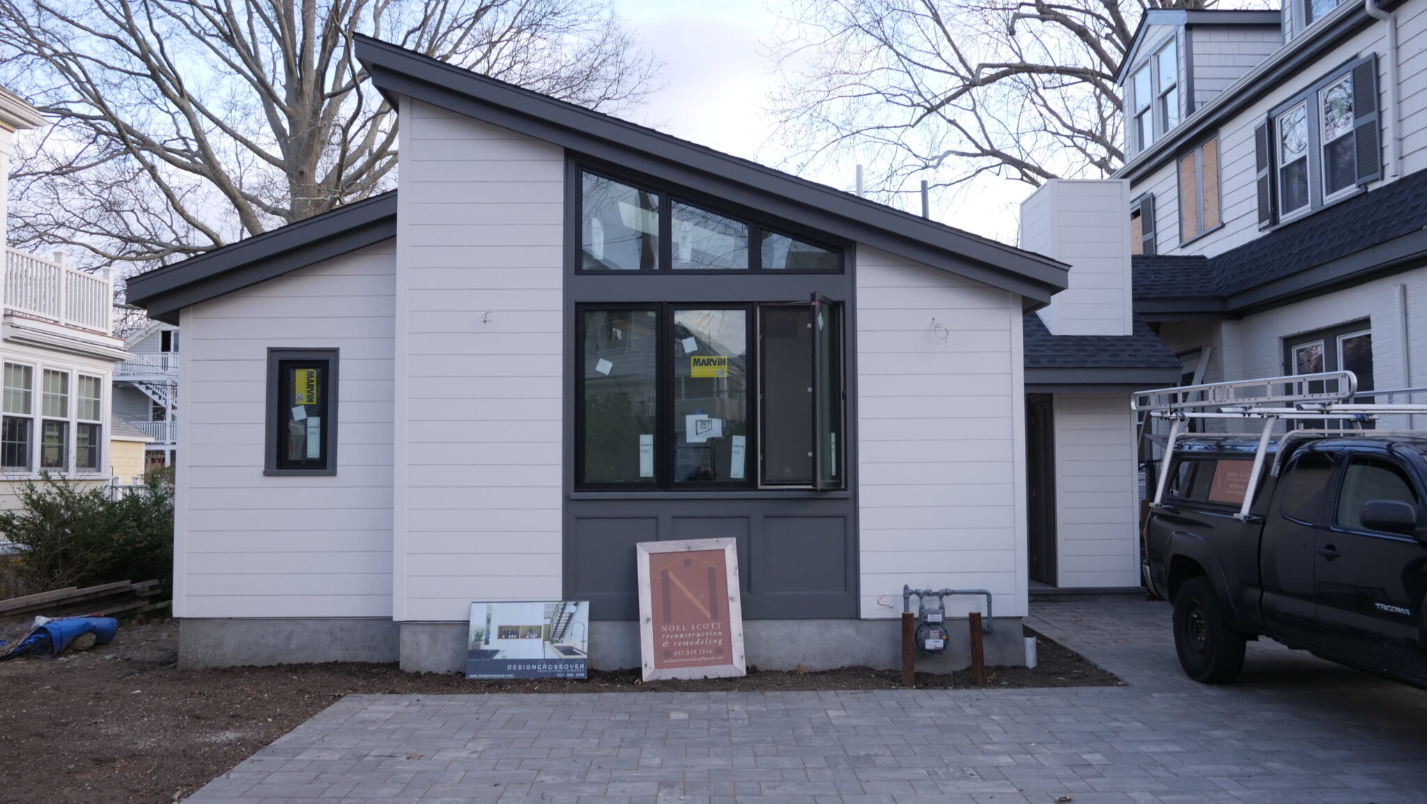 A photo of an accessory dwelling unit-type home in Massachusetts. The home is beige with a black, sloped roof, and a large window in front.