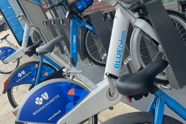A photo of four Bluebikes at a docking station on a sidewalk.