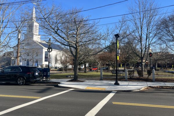 The First Congressional Church, a white building with a steeple, is pictured in Stoneham, Massachusetts with the Town Common visible to the right with a gazebo.