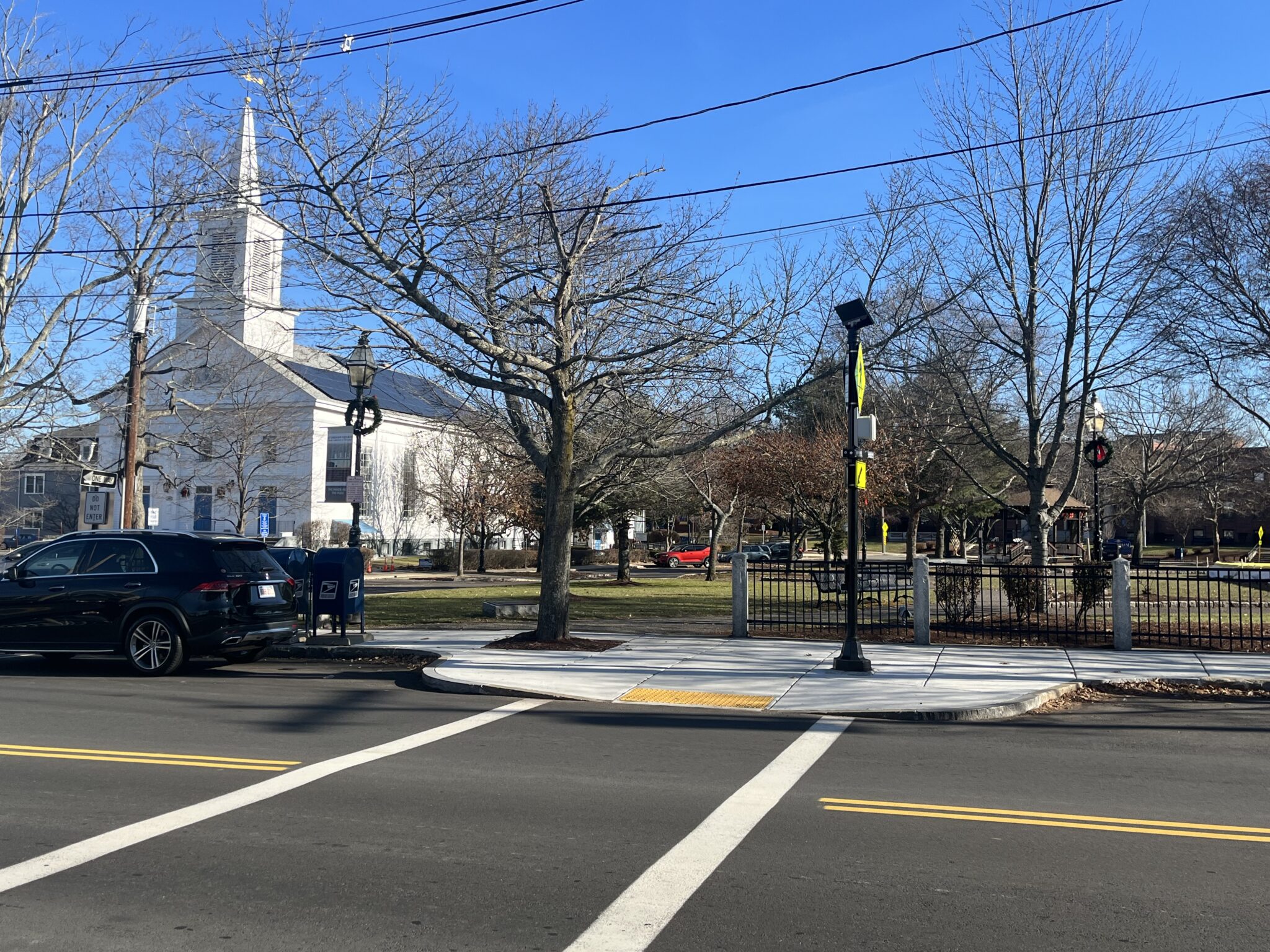 The First Congressional Church, a white building with a steeple, is pictured in Stoneham, Massachusetts with the Town Common visible to the right with a gazebo.