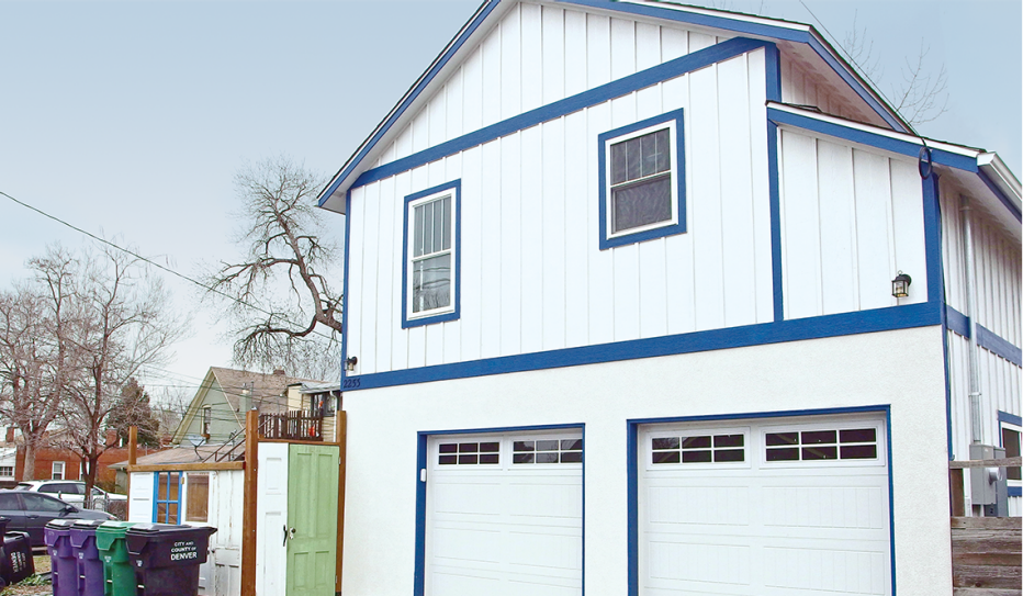 ADU of a separate house dwelling with a separate outside entrance over two garages. The house is white, two-story, with blue trim.