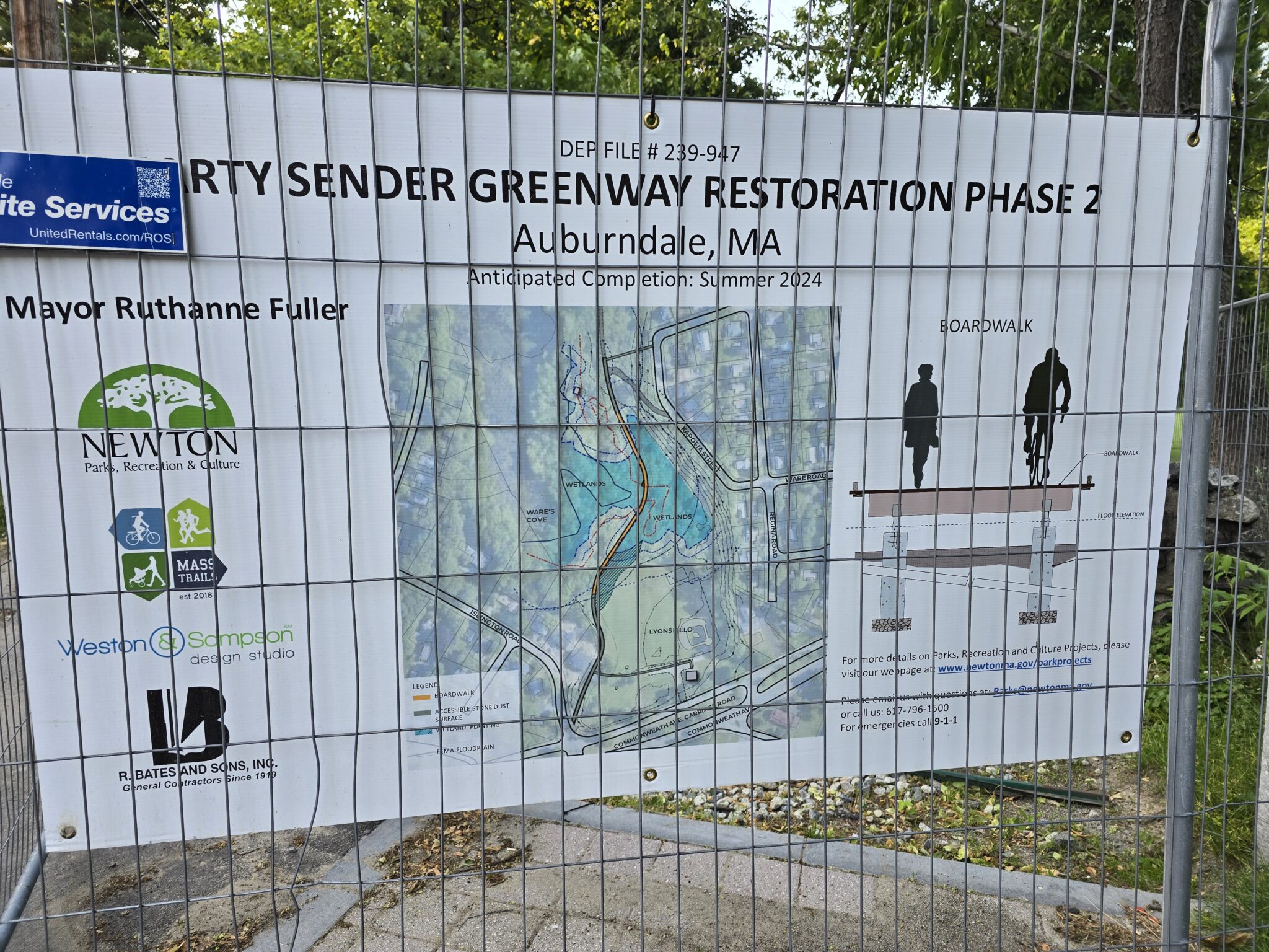 A photo from the Landline 2024 ride in Newton. Picture is of a sign that says "Marty Sender Greenway Restoration Phase 2" and includes a topographical map of the project area, diagrams, and logos.