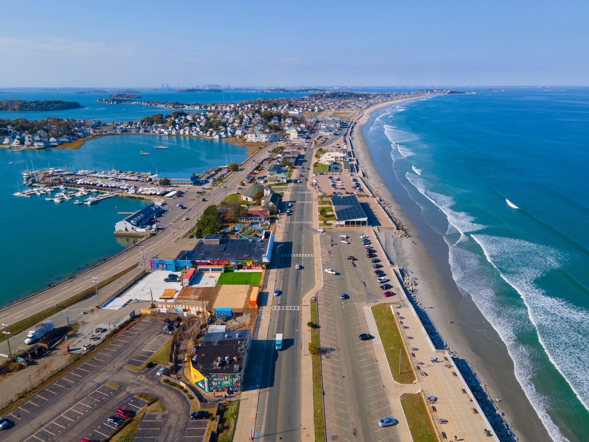 Aerial view of Nantasket Beach, Weir River, and Hingham Bay in Hull, Massachusetts. I long stretch of road and land, with water on both sides.