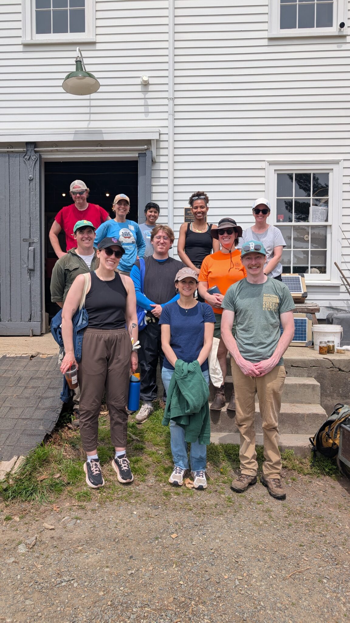 Wright-Locke Farm - NSPC A group picture of eleven individuals dressed in various colors standing in three rows in front of a white barn.