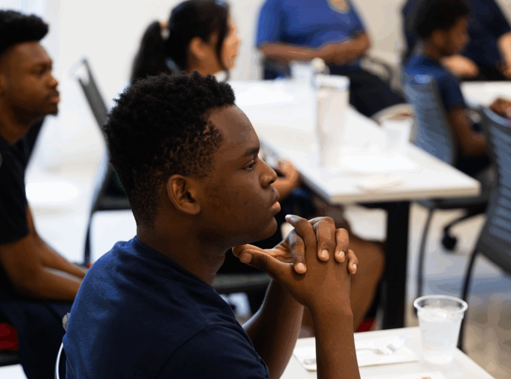 Close up photo of a student looking towards a demonstration in Boston University's demonstration kitchen as part of the Shannon Youth Conference.