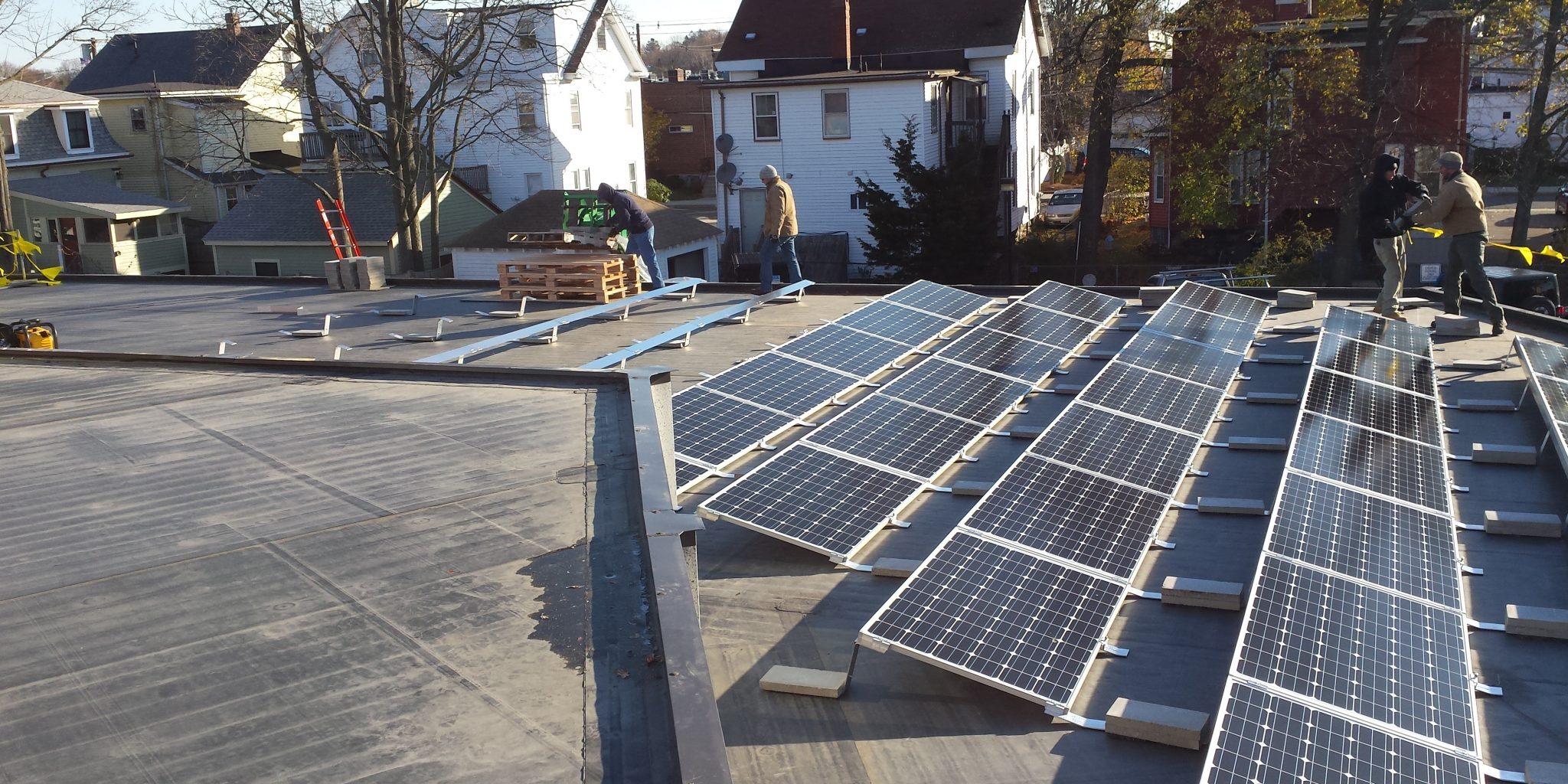 Image shows solar panels being installed on a large roof