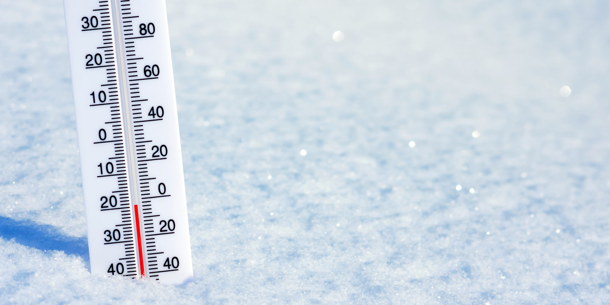 Winter background with thermometer in clean shiny snow. A thermometer is sticking out of a blanket of white snow.