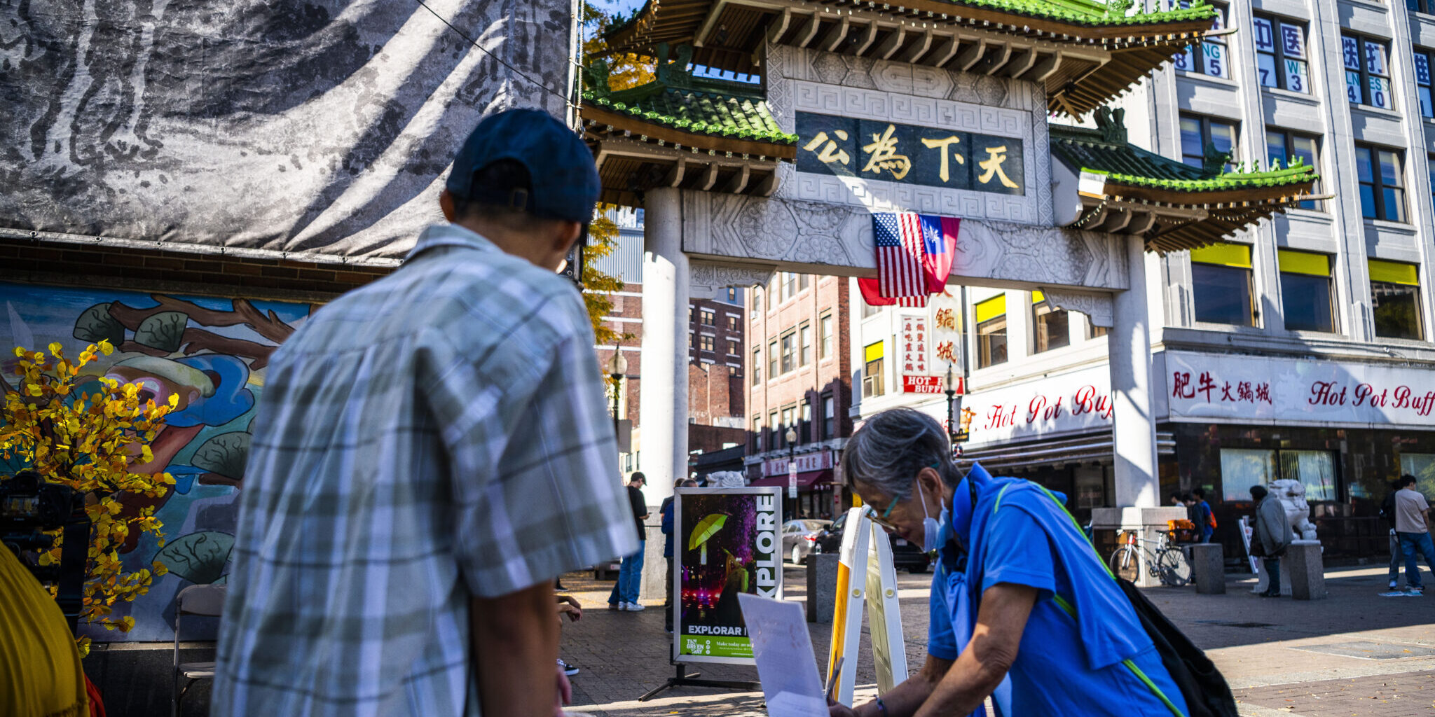 Chinatown Cultural Plan2025 A photo of Chinatown in Boston. One person is tabling, and another person is filling out information at the table.