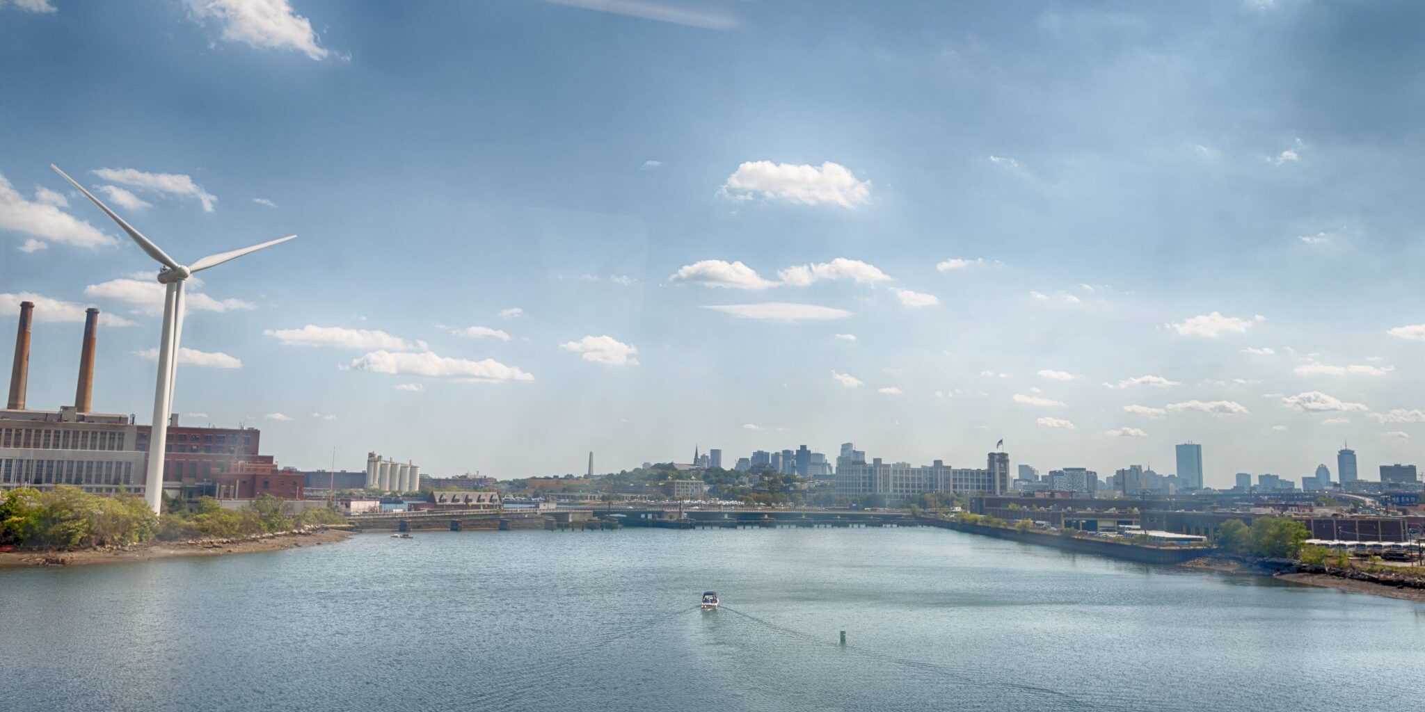 Looking through train window at Boston Boston, Massachusetts, USA - September 14, 2016: Looking through a train window at the passing scenery of Boston's skyline seen in the distance while a boat makes it's way down the water that separates the city and it's industrial area.