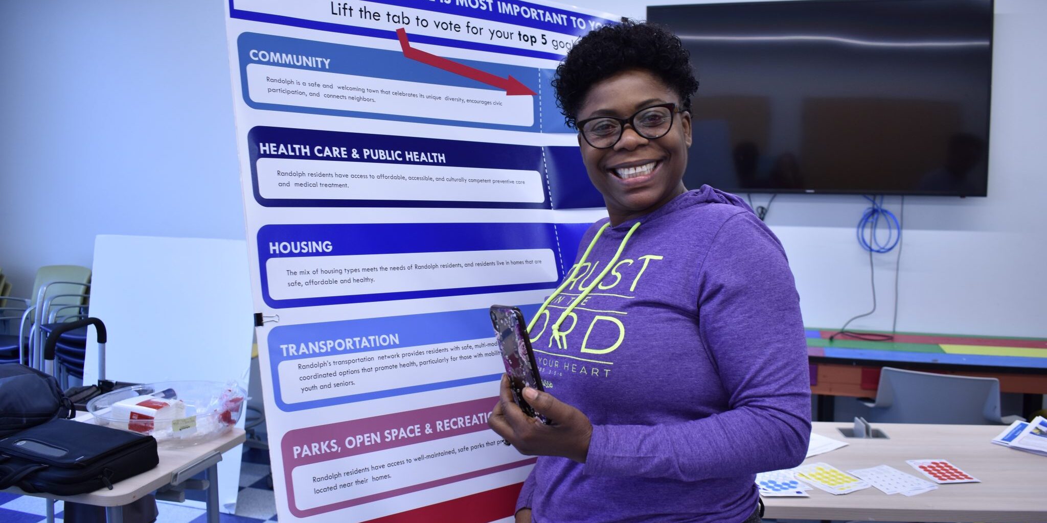 A person standing in front of a sign smiling at the camera.