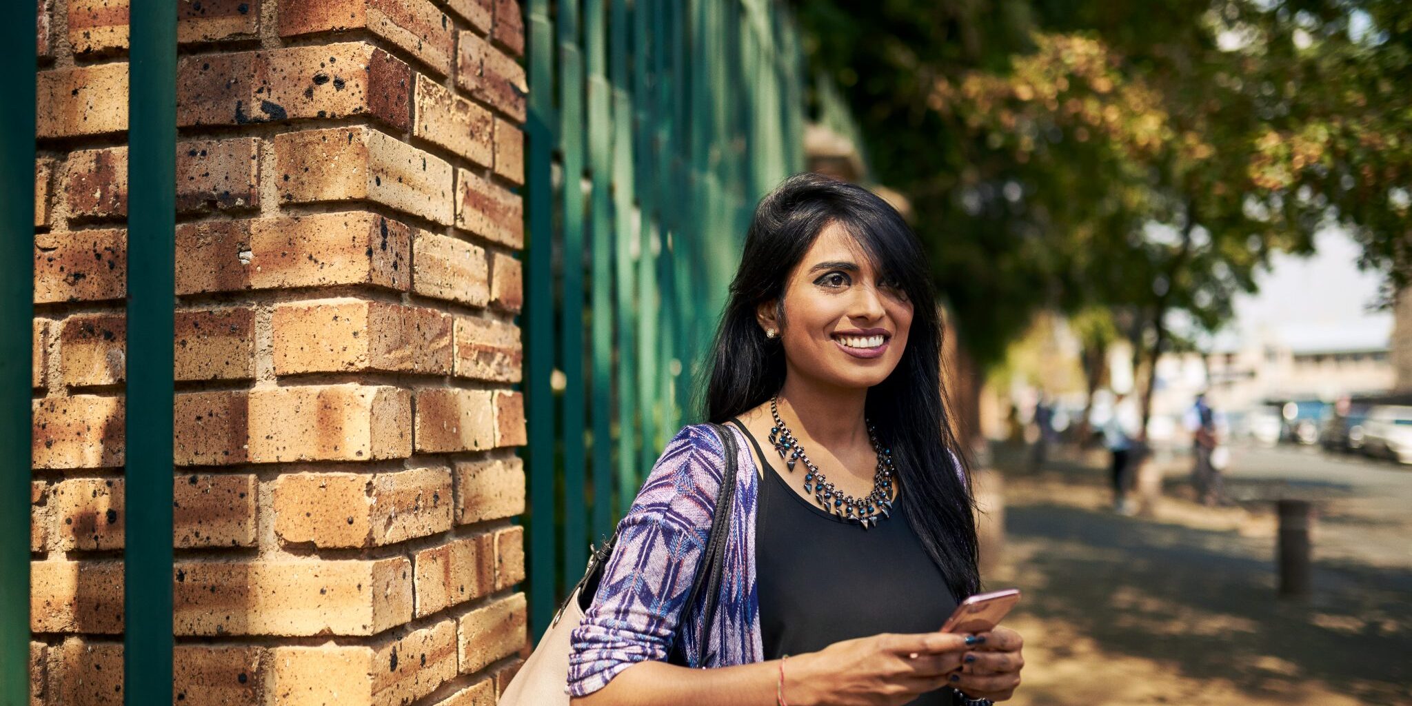 Uber, Carsharing, Ridesharing Photo Medium shot of a young woman smiling while standing on a street waiting for her ride